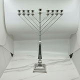 Silver Menorah on a white marble surface with a white curtain background